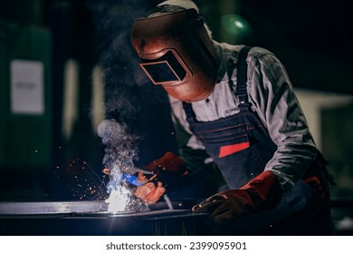 A repairman is welding metal parts in heavy industry plant. - Powered by Shutterstock