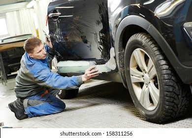 repairman worker in automotive industry stopping car body before painting or repaint at auto repair shop