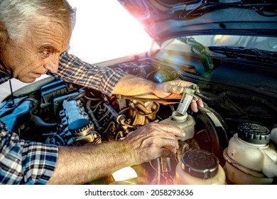 Repairman's Male Hands Checking The Level Of The Brake Fluid. Vehicle Fitter Inspecting Used Car Engine. The Labor Arm Close Up In The Open Hood Of The Car. Service Center, Auto Repair Shop