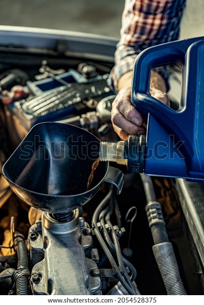 Repairman\'s male hands pouring oil from the canister\
into the engine. Vehicle fitter inspecting used car engine. Service\
center, auto repair\
shop