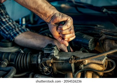 Repairman's male hands with a wrench. Vehicle fitter inspecting used car engine. Car components, belts, hoses, labor arm close up in the open hood of the car. Service center, auto repair shop - Shutterstock ID 2054526236