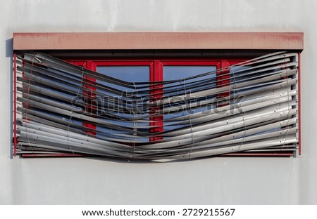 Repairs Needed - Red windows with broken exterior venetian blinds on residential building facade