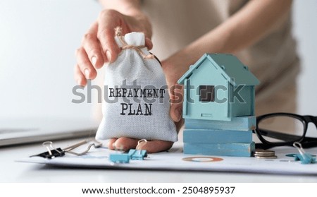 Repayment Plan text on bag ind hands and miniature house.