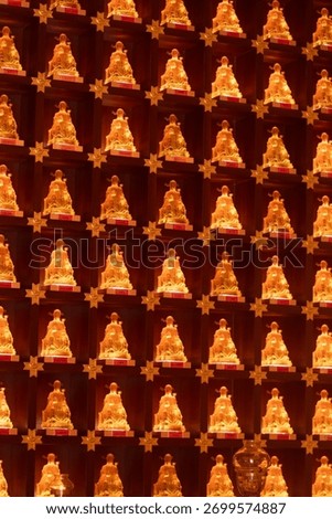 Repeated religious objects in a temple, gold and orange, symbolizing luck, fortune, and abundance, including lanterns and figures, with decorative patterns throughout.