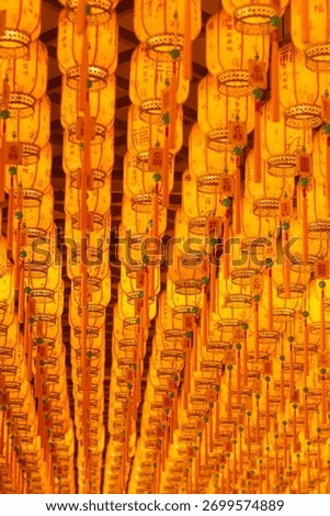 Repeated religious objects in a temple, gold and orange, symbolizing luck, fortune, and abundance, including lanterns and figures, with decorative patterns throughout.