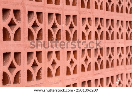 Repeating diamond pattern in red brick. Abstract background. Close-up of aesthetic red clay bricks wall with ventilation holes.