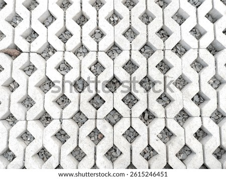 The repeating geometric pattern and rough texture of porous concrete paving blocks filled with gray gravel