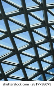 A repeating pattern of intersecting metal beams forms a geodesic dome structure, allowing sunlight to filter through glass panels