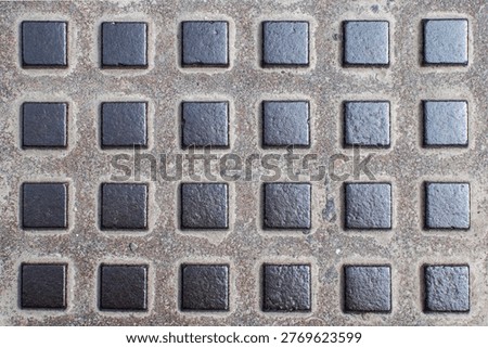 Repeating square metal pattern on aged grey industrial background.