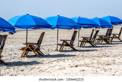 repeating wooden beach chairs and blue umbrellas on a sandy beach on Hilton Head Island, USA