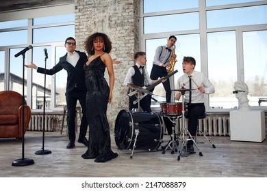 Repetition Of Multi Ethnic Jazz Band In Loft. Bass Guitar Player, Electric Guitar Player, Saxophonist And Drummer At Loft. Jazz Music And Jam Session Concept. Passion For Music And Youth Culture