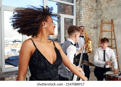 Repetition Of Multi Ethnic Jazz Band In Loft. Bass Guitar Player, Electric Guitar Player, Saxophonist And Drummer At Loft. Jazz Music And Jam Session Concept. Passion For Music And Youth Culture