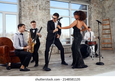 Repetition Of Multi Ethnic Jazz Band In Loft. Bass Guitar Player, Electric Guitar Player, Saxophonist And Drummer At Loft. Jazz Music And Jam Session Concept. Passion For Music And Youth Culture