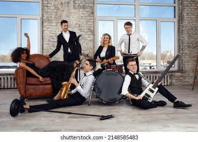 Repetition Of Multi Ethnic Jazz Band In Loft. Bass Guitar Player, Electric Guitar Player, Saxophonist And Drummer At Loft. Jazz Music And Jam Session Concept. Passion For Music And Youth Culture