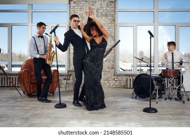 Repetition Of Multi Ethnic Jazz Band In Loft. Bass Guitar Player, Electric Guitar Player, Saxophonist And Drummer At Loft. Jazz Music And Jam Session Concept. Passion For Music And Youth Culture