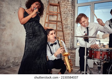 Repetition Of Multi Ethnic Jazz Band In Loft. Bass Guitar Player, Electric Guitar Player, Saxophonist And Drummer At Loft. Jazz Music And Jam Session Concept. Passion For Music And Youth Culture