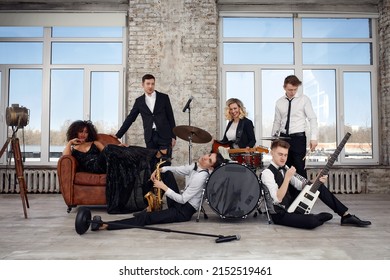 Repetition Of Multi Ethnic Jazz Band In Loft. Bass Guitar Player, Electric Guitar Player, Saxophonist And Drummer At Loft. Jazz Music And Jam Session Concept. Passion For Music And Youth Culture