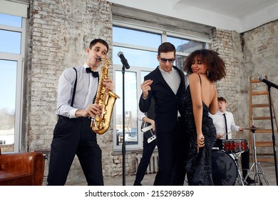 Repetition Of Multi Ethnic Jazz Band In Loft. Bass Guitar Player, Electric Guitar Player, Saxophonist And Drummer At Loft. Jazz Music And Jam Session Concept. Passion For Music And Youth Culture