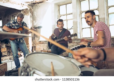Repetition of rock music band. Bass guitar player, electric guitar player and drummer at loft. Rock music and jam session concept. passion for music and youth culture concepts - Powered by Shutterstock