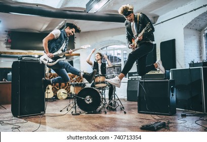 Repetition of rock music band. Bass guitar player, electric guitar player and drummer behind the drum set. Rehearsal base - Shutterstock ID 740713354