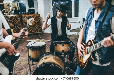 Repetition of rock music band. Cropped image of bass guitar player, electro guitar player and drummer behind the drum set. Rehearsal base - Powered by Shutterstock