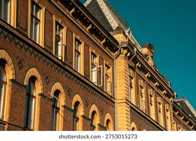 Repetitive pattern of arched windows on a historic brick building facade with ornamental tiles.