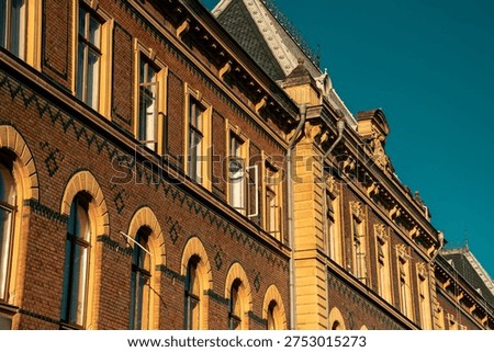 Repetitive pattern of arched windows on a historic brick building facade with ornamental tiles.