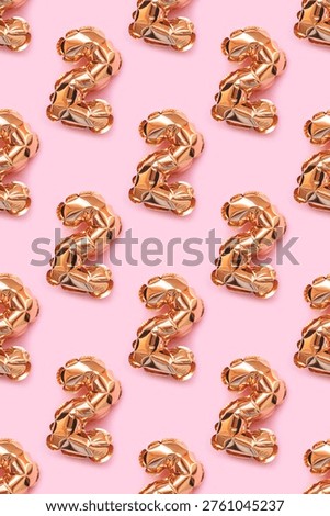 Repetitive pattern made of number two golden balloons on a pink background. 