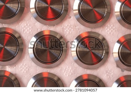 Repetitive Pattern Of Metal Push Button Switches With Red Reflections