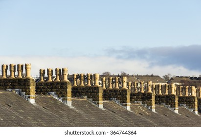 Repetitive Symmetrical Pattern Of Stone Chimneys On A Row Of Terraced Houses In Northern England. The Chimney Pots Are Clearly New And Identical, Indicating A Recent Refurbishment Programme.