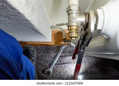 Replace old radiator thermostat valve. Pliers removes component from the heater. Modernization of heating systems. Top view. - Shutterstock ID 2121637604