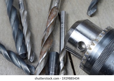 replaceable drill chuck and old drill bits lie on a wooden plank background. close-up. - Shutterstock ID 1929885434
