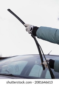 Replacement Of Car Wiper Blades, Seasonal Vehicle Maintenance, Female Hands With Warm Gloves On The Background Of Vehicle Windshield Outdoor At Cold Winter Day