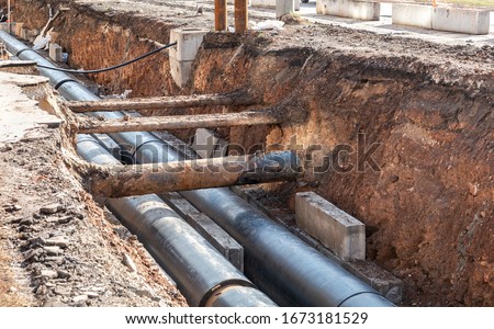 Replacement of heating pipes and modernization of the heating system. Repair of old rusty metal pipes. Construction works on large iron pipes at a depth of excavated trench
