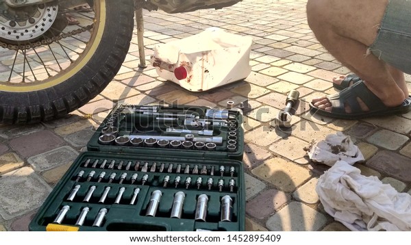 replacement of lubricating oil in a\
motorcycle. man drains dirty waste oil from a\
motorcycle.