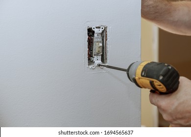 Replacement of the old switch with a new one in closeup of hand of electrician installing wall outlet