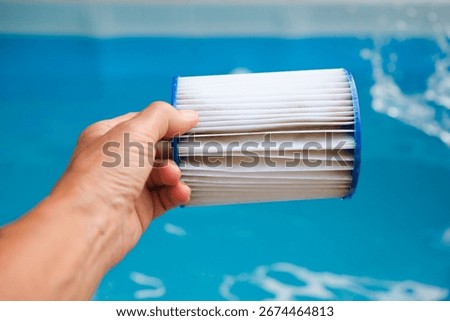 Replacement Pool Filter Cartridge in a Woman's Hand on the Blue Family Pool Background. Filter Reuse.