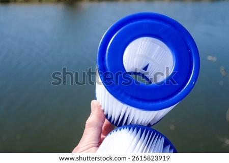 Replacement Pool Filter Cartridges in a Woman's Hand on the Water Backdrop. Water Treatment, Pool Cleaning, Water Quality, Concept. Filter Reuse. Copy Space.