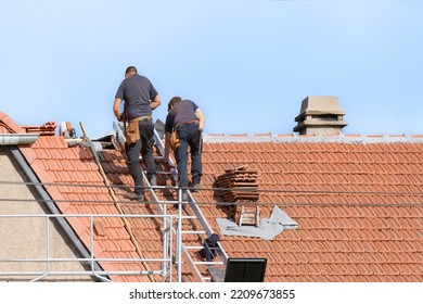 replacement of tile covering on the roof by two roofers - Shutterstock ID 2209673855
