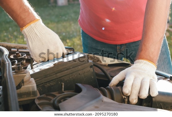 Replacing the battery before\
winter. Car maintenance before the cold season. Close up hand of\
Male mechanic changing car battery, engineer is replacing car\
battery