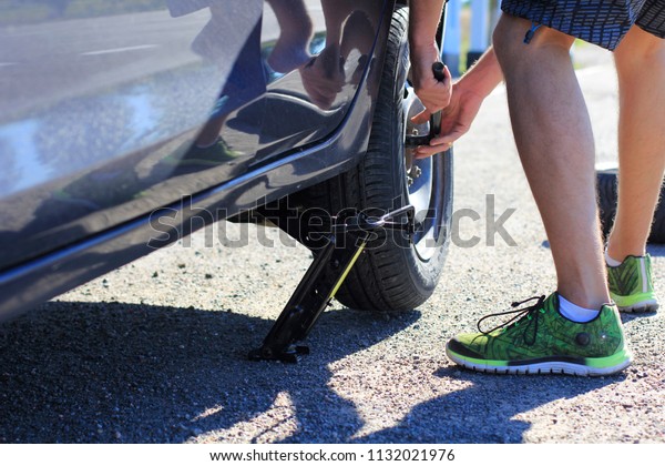 Replacing the car wheel. Photo of the car wheel\
repair process. Accident on the road. Punctured car wheel. The man\
takes off the wheel of a\
car