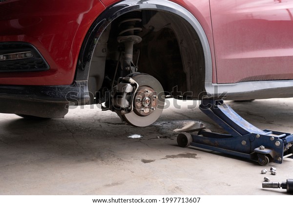 Replacing car wheel using hydraulic jack. car\
maintenance concept. Remove the wheels of the car in preparation\
for tire patch. brake discs without wheels. Automobile repair\
service center