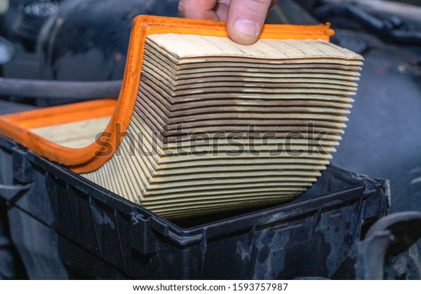 Replacing a clogged orange car air\
filter during General vehicle maintenance with a backup\
plan