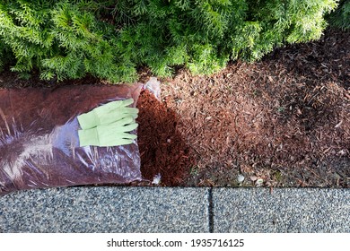 Replacing Existing Red Bark Mulch In Shrubs With Work Gloves On Top Of Open New Bag 