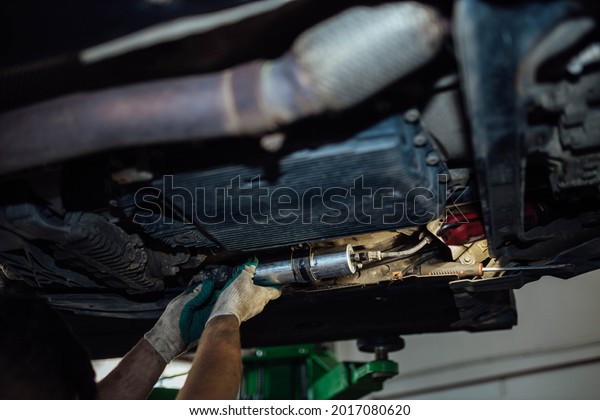 Replacing the\
fuel filter of a diesel car in a car service, dismantling the fuel\
filter under the bottom of the\
car.