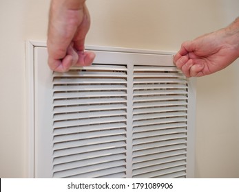 Replacing Home Cooling System Air Filter. HVAC Service Technician Opening Ventilation Grill For Heating And Air Conditioning System. Residential Air Duct System Maintenance For Clean Air.
