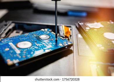 Replacing or installing a hard drive with a screwdriver on an old laptop, on a black background with flare light. The concept of upgrading a laptop computer. - Shutterstock ID 1756720328