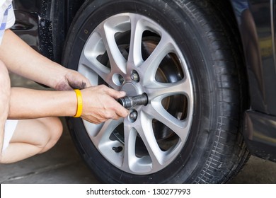Replacing lug nuts by hand while changing tires on a vehicle. - Shutterstock ID 130277993
