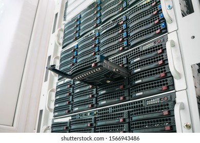 Replacing a module in a powerful server hardware. Cloud storage technology concept. Hosting platform of the Internet provider. Connect a new hard drive to a stack of computer servers. Selective focus