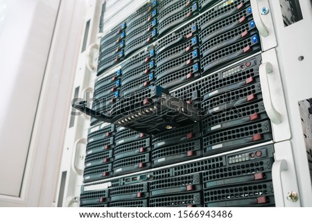 Replacing a module in a powerful server hardware. Cloud storage technology concept. Hosting platform of the Internet provider. Connect a new hard drive to a stack of computer servers. Selective focus